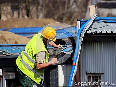 Builder in overalls at the construction site. Repairs at altitude. Construction of new buildings. The profession of a builder. Hea Editorial Stock Photo