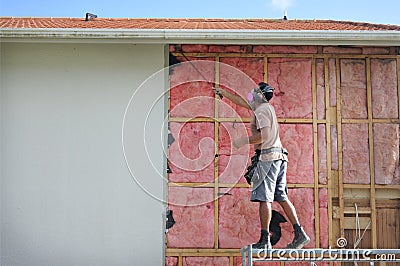 Builder removing an old fiberglass wall insulation from a building Editorial Stock Photo