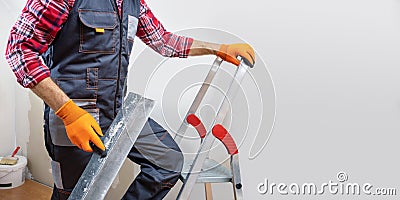 builder in work overalls plastering a wall using a construction trowel. Stock Photo