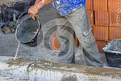 Builder worker wetting concrete with bucket of water Stock Photo