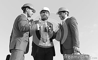 Builders discussing plan and argue, blue sky background. Stock Photo
