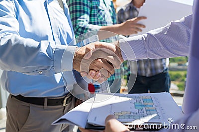 Builders Handshake Closeup, Two Building Business Men Making Deal After Discussion Of Blueprint To New Project With Stock Photo