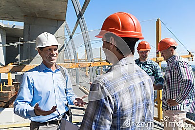 Builders Meeting On Construction Site Architect Talking With Contractor Over Group Of Apprentice Stock Photo