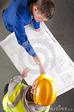 Builders shake hands over blueprint Stock Photo
