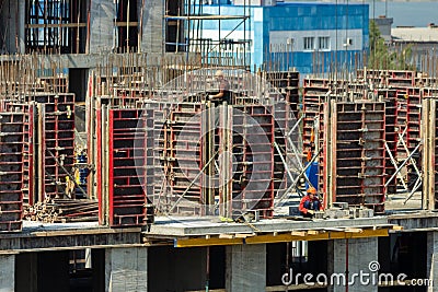 Builders are working on a construction site, assembling the frame of a high-rise building from rebar, cement blocks and others Editorial Stock Photo