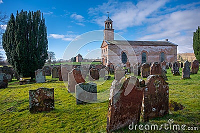 Building and cemetery stones of Kirkandrews under the blue sky with clouds in Carlisle Stock Photo