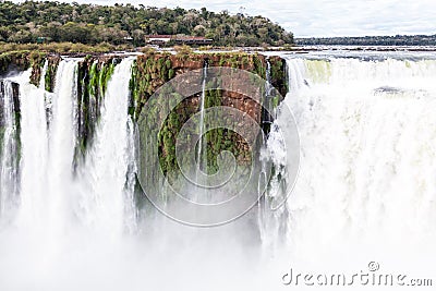 Building on a cliff over waterfall. Winter view of Iguazu Falls Devil's Throat under heavy clouds lead sky. Argentina. Stock Photo