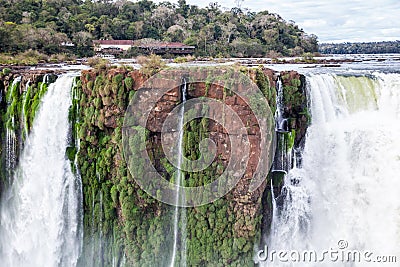 Building on a cliff over waterfall. Winter view of Iguazu Falls Devil's Throat under heavy clouds lead sky. Brazil. Stock Photo