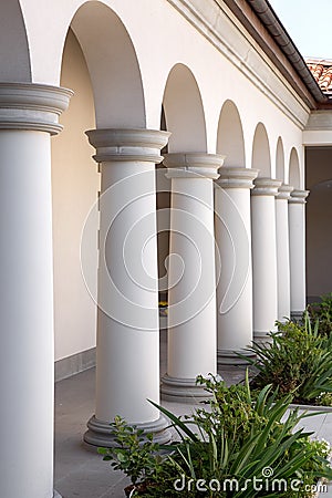 A building with columns and arched openings at the building with flowerbeds. Stock Photo