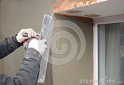 Building contractor plastering wall with fiberglass mesh, stucco, plaster mesh after rigid insulation Stock Photo