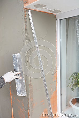 Building contractor plastering wall window corner with fiberglass mesh, plaster mesh after rigid insulation in window sill problem Stock Photo