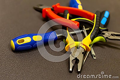 Building design close-up of a bunch of yellow open black chrome cutters screwdrivers on a brown background Stock Photo