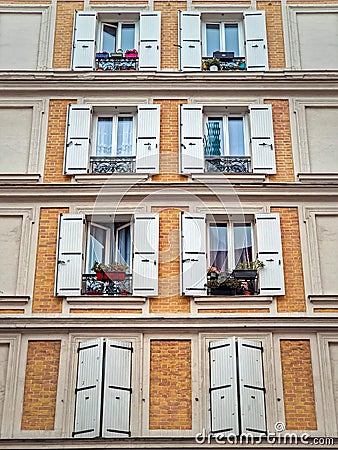 Building facade with yellow painted walls of brick masonry and windows with white outdoors louvers Stock Photo