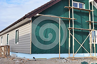 Building house with wall insulation, waterpfoof membrane, plastic siding, guttering and foundation insulation with styrofoam. Stock Photo