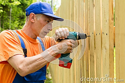 Building master with machine constructs a wooden fence Stock Photo