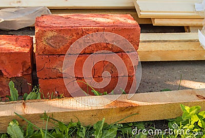 Building material for repairs in the garden-new red bricks, boards, lie on the grass Stock Photo