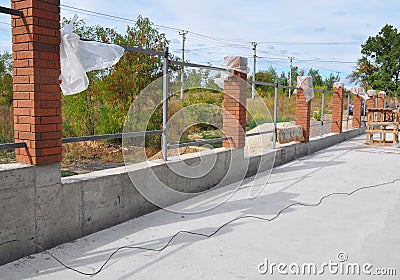 Building a Metal and Concrete, Bricks Fence with Iron Bar Stock Photo