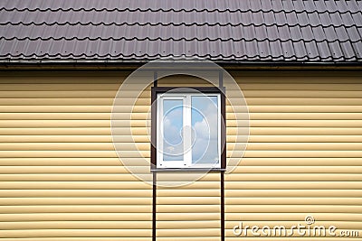 Building metal roof and wall finished with beige siding panels with white plastic window Stock Photo