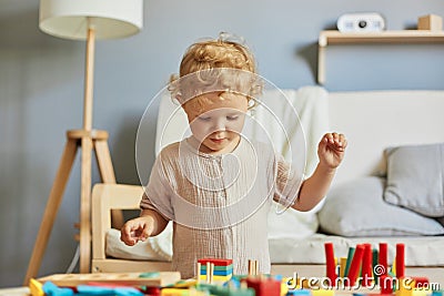 Building a playful preschooler. Learning through play. Focused wavy haired blonde infant baby playin Stock Photo