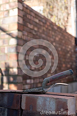 Building site: trowel, bricks and mortar for brickwork, part of a renovation of an Edwardian suburban house in north London, UK Stock Photo
