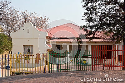 The building of a small kindergarten behind a colorful fence Stock Photo