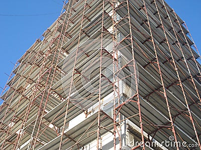 Building under rehabilitation with walls covered by metal scaffolds Stock Photo