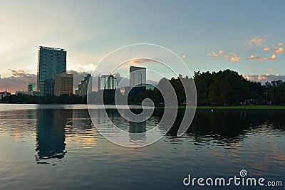 Buildings and forest reflected in lake in beautiful sunset at Eola Lake Park. Editorial Stock Photo