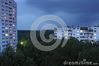 Buildings plunged in the forest lights in windows cloudy sky night view. Outskirts of Kyiv, Ukraine Stock Photo