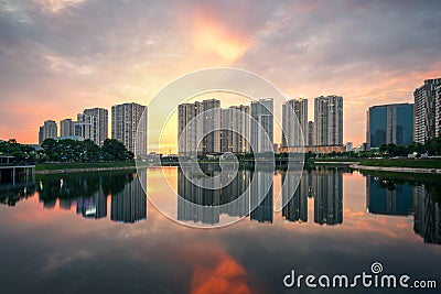 Buildings with reflections on lake at sunset at Thanh Xuan park. Hanoi cityscape at twilight period Stock Photo