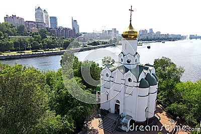 Buildings and skyscrapers in city Dnipro, Ukraine. Beautiful white christian Orthodox church near river. Ukrainian summer Stock Photo