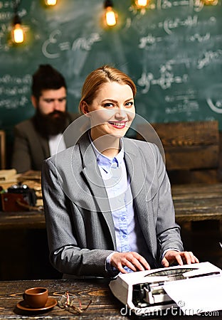 Buiness woman type on vintage typewriter with blurred man on background. Sensual girl typewrite research paper. Happy Stock Photo