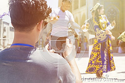 BUKHARA, UZBEKISTAN - MAY 25, 2018: Silk and Spices Festival 2018. Young man taking selfie with bukharian musicians and dancers Editorial Stock Photo