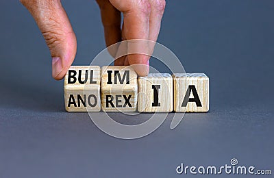 Bulimia or anorexia symbol. Doctor turns wooden cubes and changes the word anorexia to bulimia. Beautiful grey table, grey Stock Photo