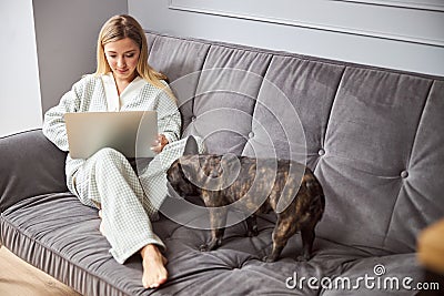 Bulldog smelling a woman with laptop on bed Stock Photo