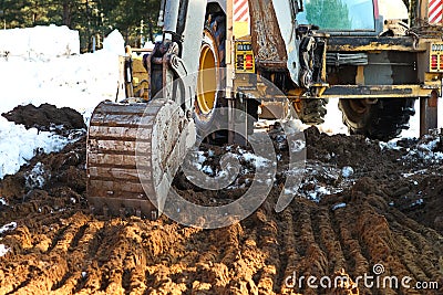 Bulldozer bucket close-up digs a pit for the construction. The foundation of the house, earthworks. The excavator shovels out the Editorial Stock Photo