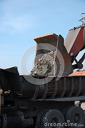 Bulldozer with bucket loads stones in truck Stock Photo