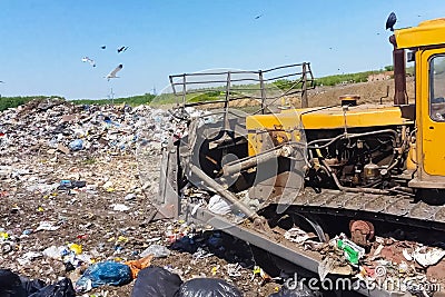 A bulldozer clears heaps of garbage in a garbage can. Work bulldozer in a landfill Editorial Stock Photo