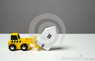 A bulldozer demolishes a house. Toy figures. Territory clearing service. Stock Photo