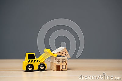 The bulldozer demolishes the old house. The building was badly damaged and cannot be used. Demolition and rehabilitation program Stock Photo