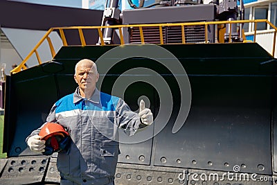 Bulldozer driver coal mine in uniform with helmet and headphones looking to side. Concept man industrial portrait Stock Photo