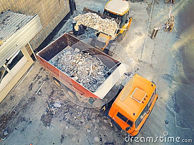 Bulldozer loader uploading waste and debris into dump truck at construction site. building dismantling and construction Stock Photo