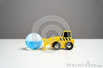 Bulldozer pushes planet earth blue globe. Stock Photo