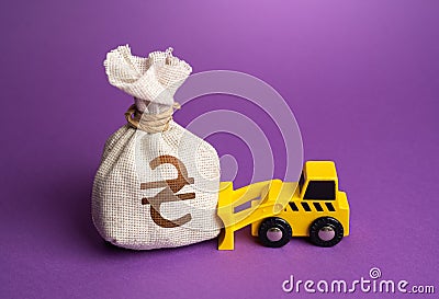 A bulldozer pushes a ukrainian hryvnia money bag. Stock Photo