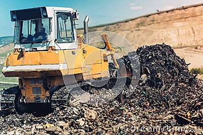bulldozer pushing garbage and working on trash site Stock Photo