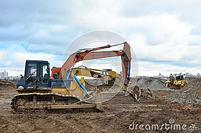 Bulldozer Shantui SD16 and Group Excavators brands of the Kraneks and CATERPILLAR with buckets Editorial Stock Photo