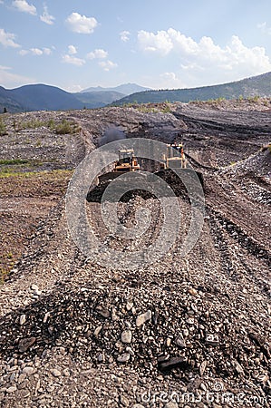 Bulldozers rake gold-bearing mountain soil into a heap Stock Photo