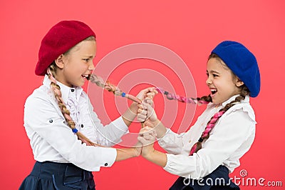 Bullying and aggression. Naughty children pulling pigtails on pink background. Small girls with bullying behavior Stock Photo