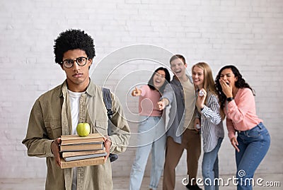 Bullying and racism, problems in college. Sad african american smart guy with glasses holds books Stock Photo