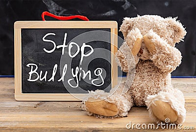 Teddy bear covering eyes and stop bullying text on a blackboard Stock Photo