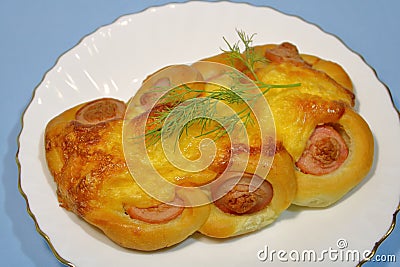 Bun with sausage on a plate on a gray background. Stock Photo